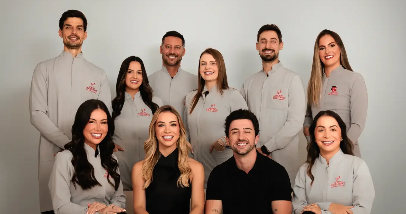 A equipe da Odonto Excellence Balneário Camboriú no estúdio, de jaleco cinza com o logo bordado